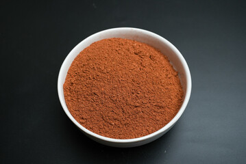 Red chili powder on a white plate on a black background