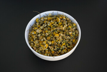 Chamomile flower on a white plate on a black background