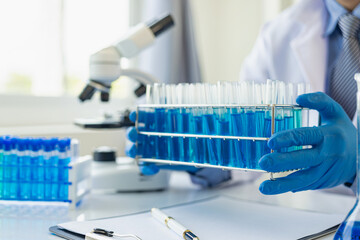 Researchers work in blue liquid test tube analyzes in chemical science laboratories or microscopic...