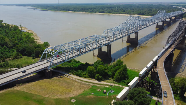Aerial view double Vicksburg Bridges carrying Interstate 20 (I-20), US Route 80 with cars and freight trains rail line across Mississippi River between Delta, Louisiana and Vicksburg