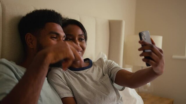 Couple at home in bed posing for selfie on mobile phone- shot in slow motion