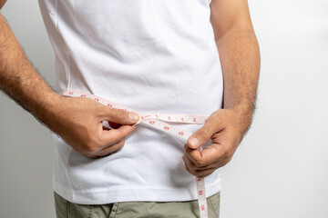 Man touching his fat belly on white background. Paunch of a man. Overweight tape measure around the...