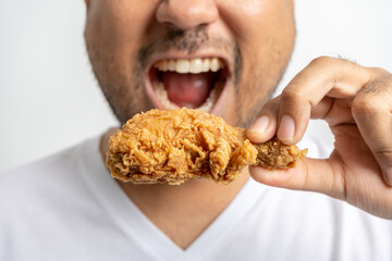 Asian Man in eating fried chicken junk food high calorie food and health risks. Hungry young man eating Fried Chicken