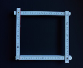 folding ruler bent into a square on a black background