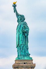 Fototapeta premium New York, New York, United States. August 07, 2023. Dramatic and detailed image of the Statue of Liberty with strong shades of green, sky with many clouds and very high resolution.