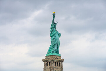 Obraz premium New York, New York, United States. August 07, 2023. Dramatic and detailed image of the Statue of Liberty with strong shades of green, sky with many clouds and very high resolution.