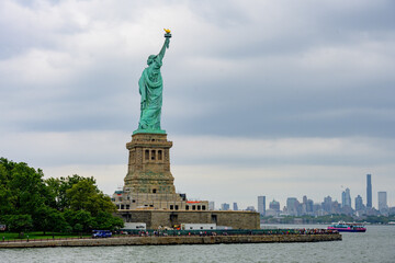 Fototapeta na wymiar New York, New York, United States. August 07, 2023. Dramatic and detailed image of the Statue of Liberty with strong shades of green, sky with many clouds and very high resolution.