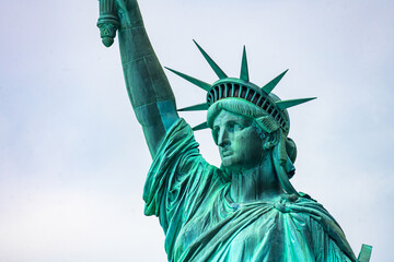 Fototapeta premium New York, New York, United States. August 07, 2023. Dramatic and detailed image of the Statue of Liberty with strong shades of green, sky with many clouds and very high resolution.