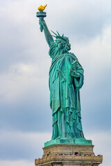 Fototapeta premium New York, New York, United States. August 07, 2023. Dramatic and detailed image of the Statue of Liberty with strong shades of green, sky with many clouds and very high resolution.