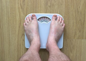 Man's feet standing on bathroom scales