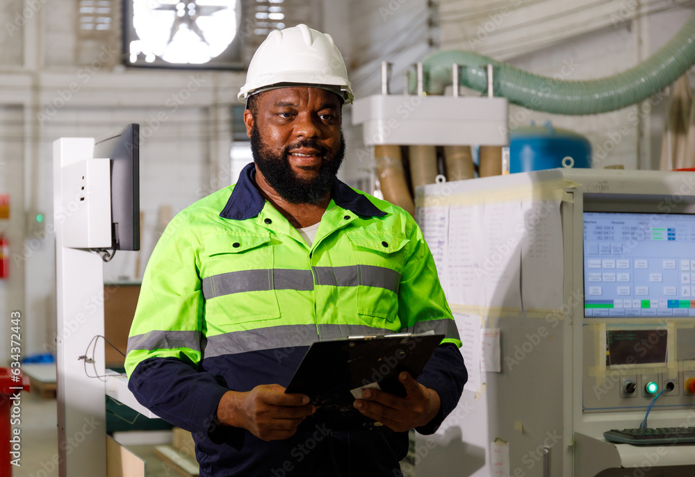Poster portrait. african male engineer using a tablet computer. the background is a cnc cutting machine in 