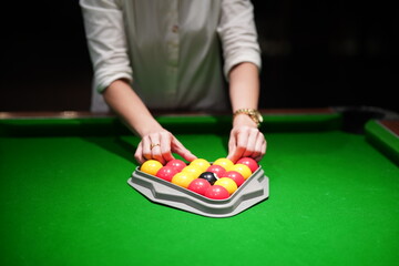 Close up of female hands racking up billiard balls.