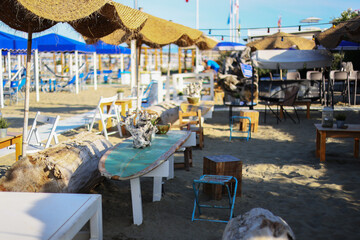 Beach club concept, food corner or cafe, restaurant tables, straw natural chairs, wooden tables