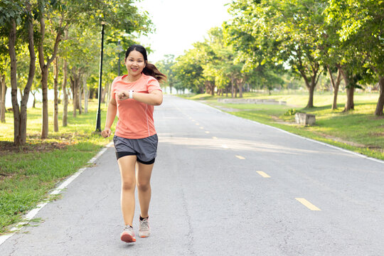 Asian Fitness woman with heart rate monitor running on park with running training during morning workout,female checking heartrate and pulse from smart watch monitor running healthy lifestyle concept.