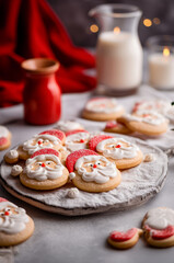 Obraz na płótnie Canvas Adorable Santa Sugar Cookies on a plate with glass jug of milk on background. Cozy festive atmosphere.