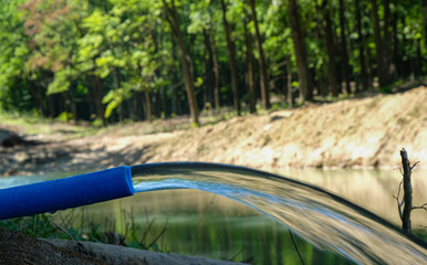 Pure water pours from a pipe. Filling a pond or reservoir with water.