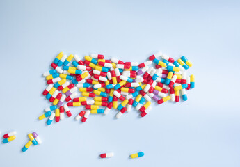 Different kinds of pills, drugs in different colours on blue background. Top view, flat lay. 