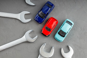 top view of toy cars on a gray surface, with wrenches around them