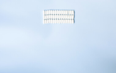 Lot of medicine pills on blue background. Scattered white pills on blue table. 