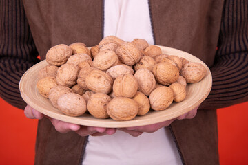 Cheerful guy with walnuts posing in the studio on an orange background.