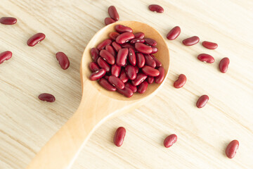 red kidney beans and spoon on wooden background, top view, flat lay, top-down, selective focus.