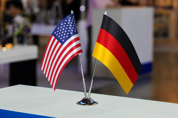 Two small table flags of the USA and Germany together at some event or fair, as a symbol of...