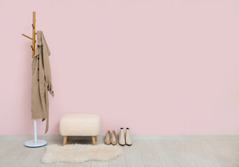 Modern bench, rack with coat and shoes near pink wall in hall