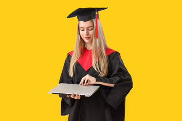 Female graduate student with laptop on yellow background