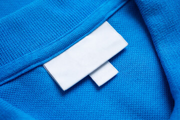 Blank white laundry care clothes label on blue shirt fabric texture background