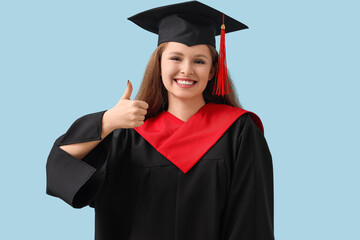 Female graduate student showing thumb-up on blue background