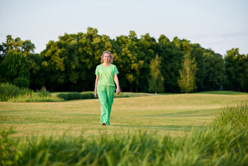 Adult energetic self-confident woman 50 years old, walking on the golf course