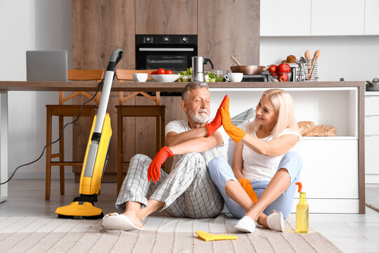 Mature couple giving each other high-five after cleaning in kitchen