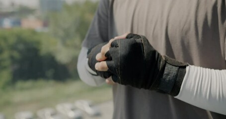 Close-up of wrapped hands of male boxer hitting fists preparing for fight in modern gym. Professional sportsman ready for practice and battle.