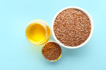Glass of flax oil and bowls with seeds on blue background