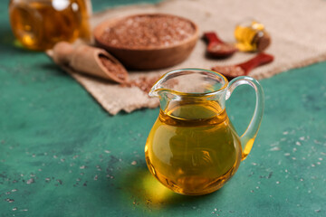 Jug with flax oil on green background