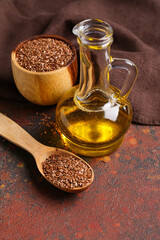 Decanter of flax oil and wooden bowl with seeds on dark background