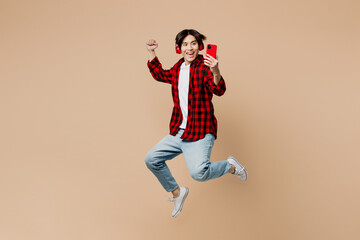 Full body side view young man of Asian ethnicity wear red shirt casual clothes jump high listen to...