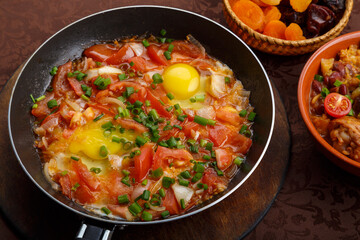 hot shakshuka in a frying pan sprinkled with green onions on the Shabbat table.