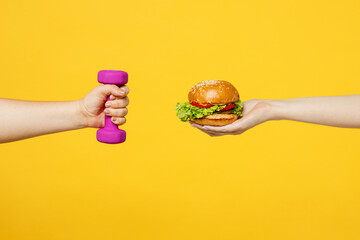 Close up cropped female hold in hand broccoli vegetable against dumbbells isolated on plain yellow color wall background studio. Healthy lifestyle motivation concept. Copy space advertising mock up.
