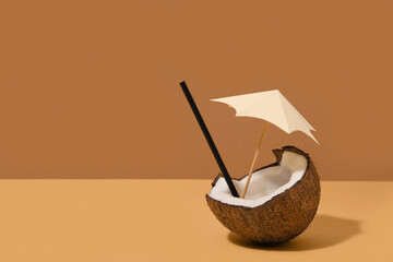 Fresh coconut with decorative umbrella on brown background