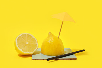 Fresh lemon with decorative umbrella on yellow background