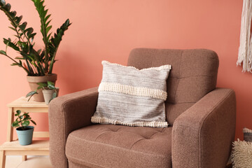 Stylish brown armchair and houseplant on stepladder near color wall