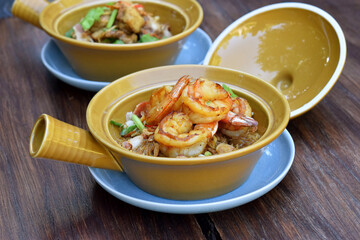 Casseroled shrimps with glass noodles in clay pot on wooden table