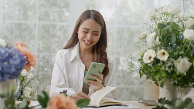 Small business,business online and New market concept.Young florist female use smartphone take photo bouquet of flower send to customer at workplace.woman artist working in flower shop studio at home