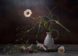 Chamomile and arrows of garlic in a vase on a dark background. Summer still life © 02irina