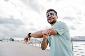 Exercise training A man in sports glasses, Uses a fitness watch on his arm. Running trainer fitness...