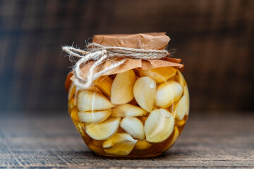 Sliced garlic cloves in honey in glass jar, closeup. Honey infused garlic