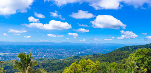 A large city background image with green mountains surrounding it. Panorama, blue sky horizon, lots...