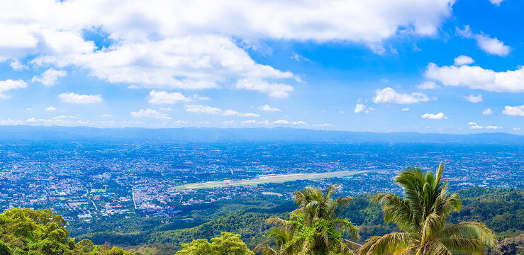 A large city background image with green mountains surrounding it. Panorama, blue sky horizon, lots of white clouds, mountains, airports, villages. Tourist attractions in Thailand.