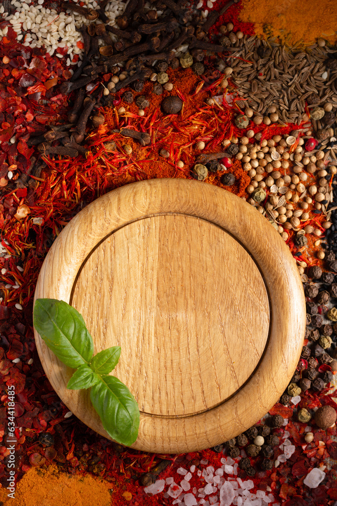 Poster Wooden plate and variety of spices at table background. Food spice and ingredients